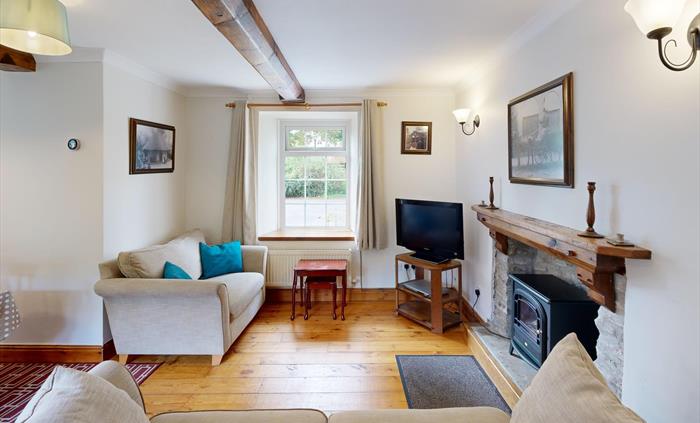 A character-filled lounge featuring exposed beams, a traditional stone fireplace with electric stove, and a family dining area in a cosy corner. Court